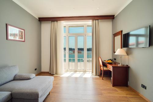 a living room with a couch and a desk and a window at BO Hotel Palazzo in Poreč