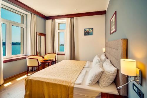 a hotel room with a large bed and windows at BO Hotel Palazzo in Poreč