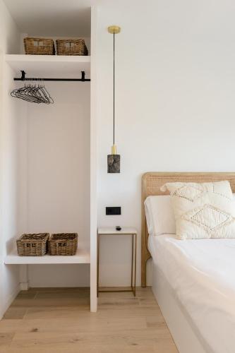 a white bedroom with a bed and a table at The Olive Boutique Suites & Spa in Cala Llonga