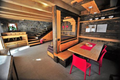 a dining room with a table and red chairs at Chalet Al Cucù in Ovaro
