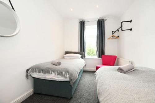 1 dormitorio con 2 camas y silla roja en Morden house close to City centre & The Peaks, en Chesterfield