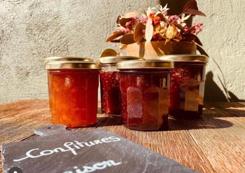 three jars of jam on a table with a plant at La maison du tripot in Honfleur