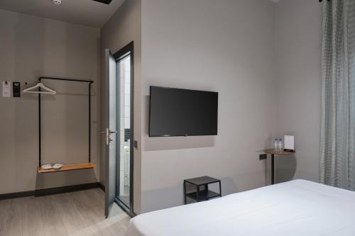 um quarto com uma cama e uma televisão de ecrã plano na parede em Sapiens Hotel em Tashkent
