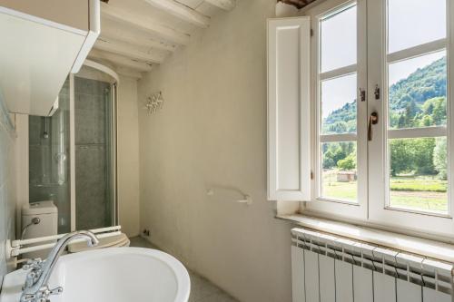 Pescaglia的住宿－Casa Paola，白色的浴室设有水槽和窗户。