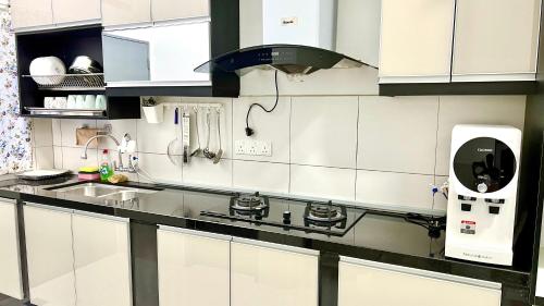 a kitchen with white cabinets and a black counter top at De Qasturee KLIA@Kota Warisan homestay nearest to airport in Kampong Besut