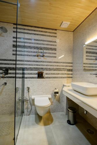 a bathroom with a toilet and a shower and a sink at Clarks Inn Suites, Manali in Manāli