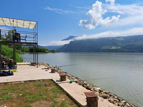a view of a body of water with a person fishing at Cazanele Dunarii "La Cumatru" in Dubova