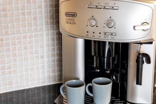 a coffee maker sitting on a counter with two cups at Royal View Apartments in Kirkby Lonsdale