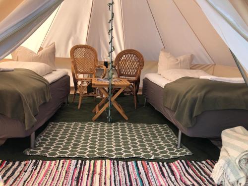 une tente avec 2 lits, une table et des chaises dans l'établissement Helles Have Glamping, à Stege