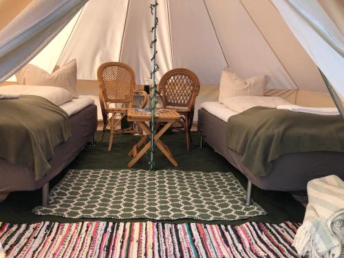 a tent with two beds and a table and chairs at Helles Have Glamping in Stege