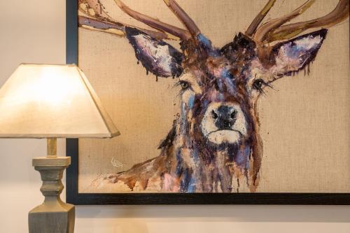 a painting of a deer on a wall next to a lamp at Royal View Apartments in Kirkby Lonsdale