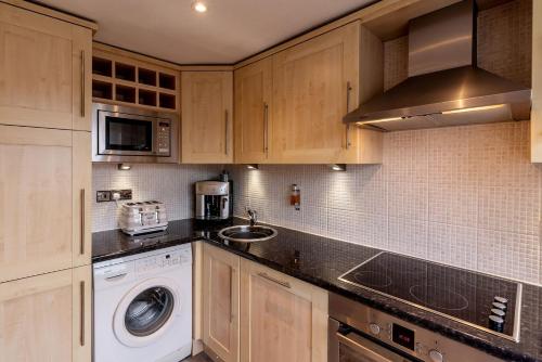 a kitchen with wooden cabinets and a washer and dryer at Royal View Apartments in Kirkby Lonsdale