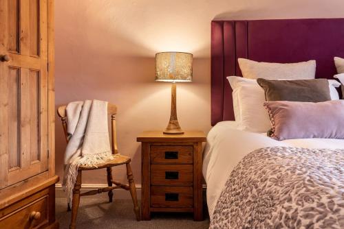 a bedroom with a bed and a lamp and a chair at Royal View Apartments in Kirkby Lonsdale