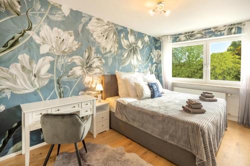 1 dormitorio con 1 cama con escritorio y un mural de flores en SweetHome - DAH02 - LUXUS PUR Apartment, Küche, TV en Dachau