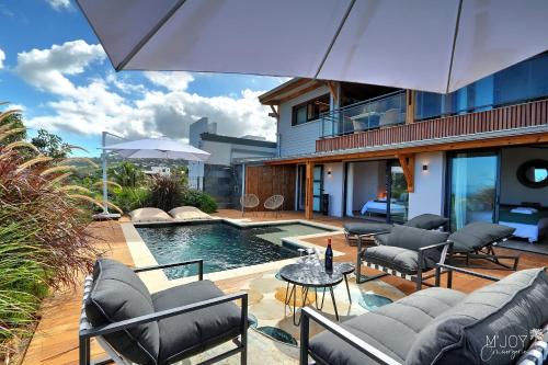 een achtertuin met een zwembad en stoelen en een huis bij VILLA AUSTRAL et LAGONS in L'Étang-Salé