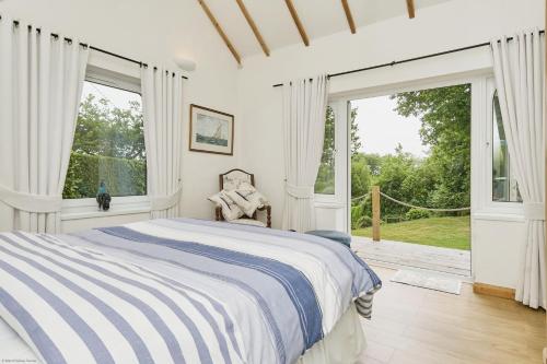 a white bedroom with a bed and large windows at Kipper Cottage in Wootton Bridge
