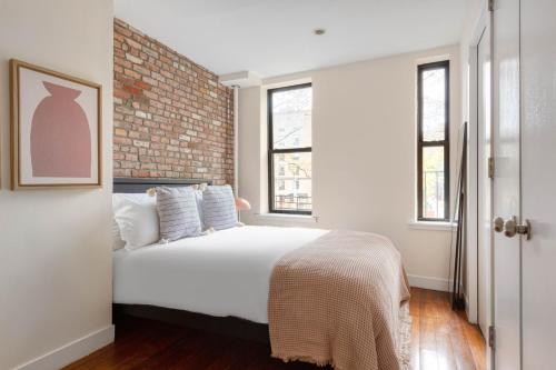 a bedroom with a white bed and a brick wall at East Village 1br w wd nr First Park NYC-1035 in New York