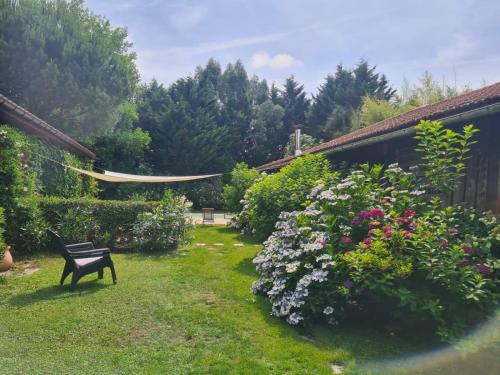 einen Garten mit einer Bank und ein paar Blumen in der Unterkunft Maison Pimoli : Chambre Garance in Soustons