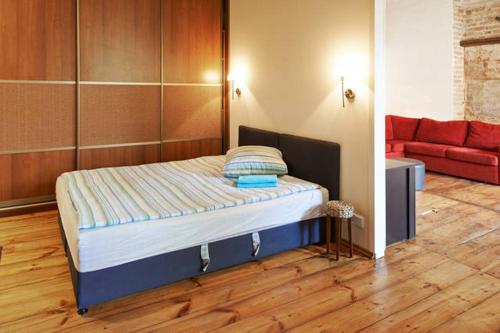 Cama en habitación con sofá rojo en Mykolo Apartments, en Vilna
