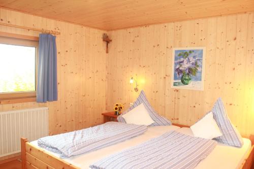 a bedroom with a bed in a room with wooden walls at Ferienhaus Talblick in Weiler-Simmerberg