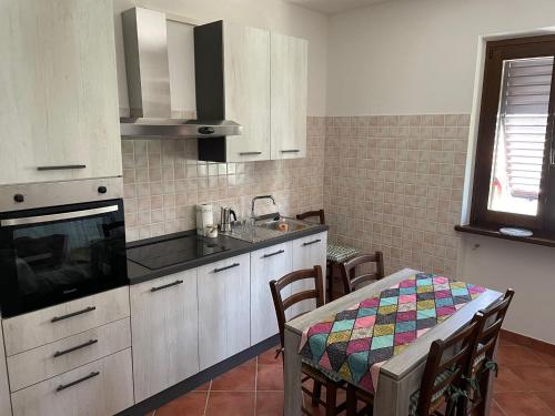 cocina con armarios blancos, mesa y fregadero en Villa Lori, en Fornaci di Barga
