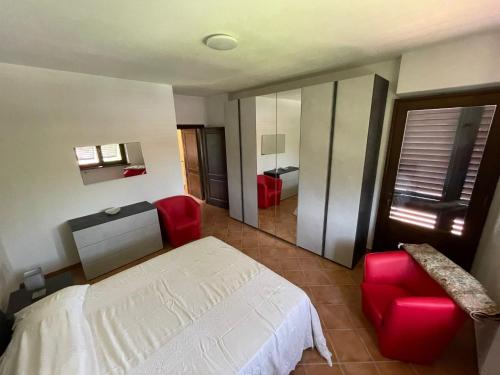 1 dormitorio con 1 cama y 2 sillas rojas en Villa Lori, en Fornaci di Barga