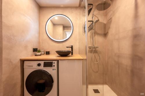 uma casa de banho com uma máquina de lavar roupa e um espelho. em Esprit du Sud Le Rocher d'Azur em La Rouviere