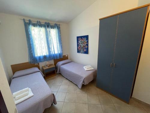 Habitación pequeña con 2 camas y puerta en Residence Il Borgo di Porto Corallo en Villaputzu