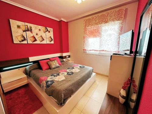 ein Schlafzimmer mit einem Bett mit einer roten Wand in der Unterkunft Apartamento Vistamar III REF. 039 in El Borseral