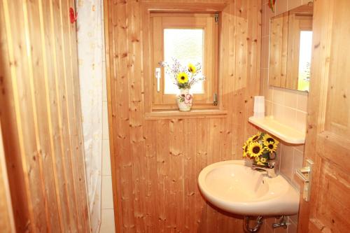 un baño con lavabo y un jarrón de flores en una ventana en Ferienhaus Talblick en Weiler-Simmerberg