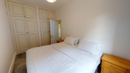 sypialnia z białym łóżkiem i drewnianą szafką w obiekcie The Bardwell w Oksfordzie
