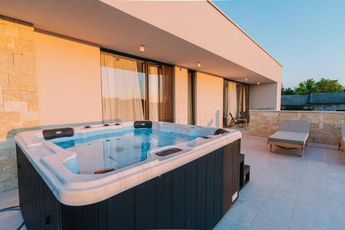 eine Whirlpool-Badewanne auf dem Balkon eines Hauses in der Unterkunft CROWONDER Santa Barbara Majestic Villa with Large Heated Swimming Pool and Sauna in Privlaka