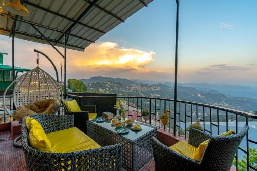 a balcony with chairs and tables and a view of the mountains at ArtBuzz Mussoorie in Mussoorie