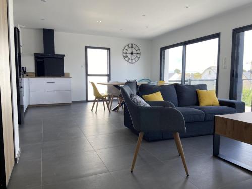 un salon avec un canapé bleu et une table dans l'établissement Appartement avec terrasse vue mer, parking privé (lgt B), à Ploemeur