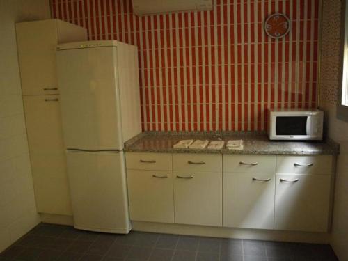 W kuchni znajduje się biała lodówka i kuchenka mikrofalowa. w obiekcie Hostel Bardenas w mieście Cabanillas
