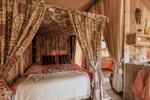 a bedroom with a canopy bed with curtains at Kampari in Delfstrahuizen