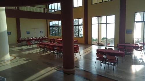 a large room with tables and chairs and windows at Shiv Sagar Palace,Ganpatipule in Ganpatipule