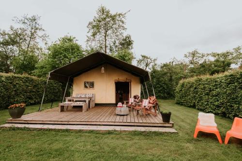 a yurt with a deck and chairs in a yard at Kampari in Delfstrahuizen