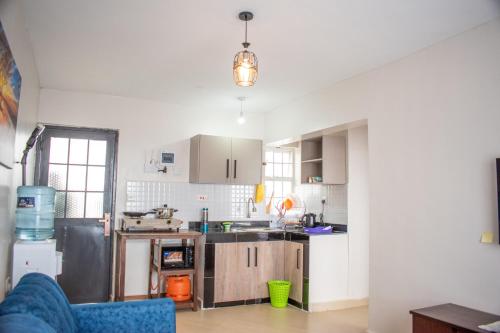 cocina con armarios blancos y sofá azul en Shalom Studio city Apartments., en Naivasha