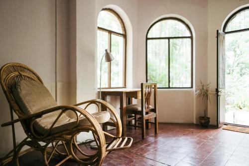 a living room with a table and chairs and windows at Laika Heritage Stay in Mysore