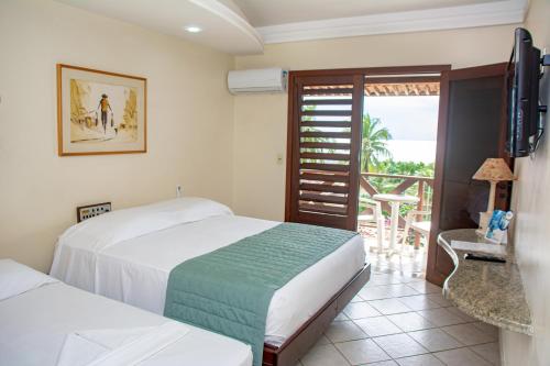 a bedroom with two beds and a television and a balcony at O Tempo e o Vento in Natal