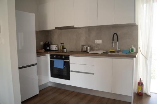 a kitchen with white cabinets and a black stove at Naiads Nest - The Comfort Lux in Varkiza