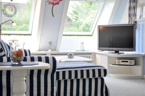 a living room with a tv and two chairs and a table at Inselhotel Arfsten in Wyk auf Föhr