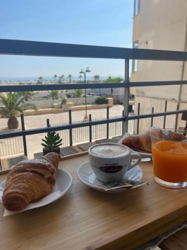a table with a breakfast of croissants and a cup of coffee at Alma Salina Suite in Margherita di Savoia