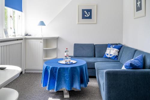 ein Wohnzimmer mit einem blauen Sofa und einem Tisch in der Unterkunft Inselhotel Arfsten in Wyk auf Föhr