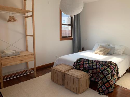 a bedroom with a bed with a ottoman next to it at Ferreira Borges Nomadic Ap A in Porto