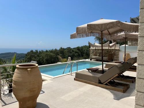 a villa with a swimming pool with chairs and an umbrella at Goldeneye luxury Villas in Parga