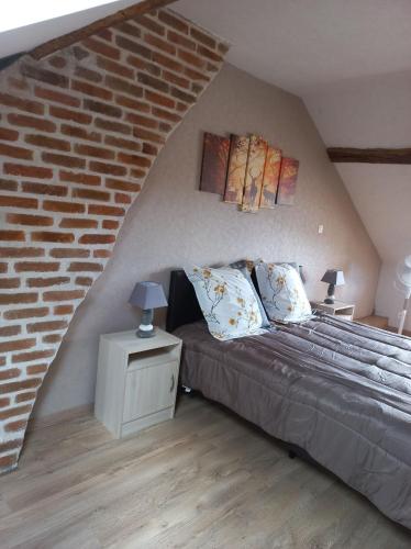 une chambre avec un lit et un mur de briques dans l'établissement maison chaleureuse solognote mitoyenne, à La Ferté-Saint-Aubin