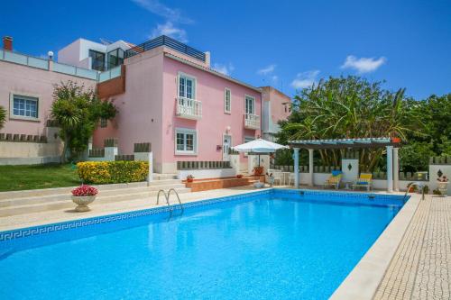 a swimming pool in front of a pink house at Pata da Gaivota Boutique House in Lourinhã