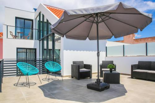an umbrella sitting on top of a patio with chairs at Pata da Gaivota Boutique House in Lourinhã